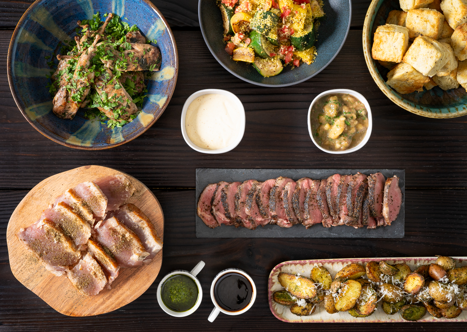 An artfully arranged assortment of gourmet dishes, including sliced meats, roasted vegetables, and a vibrant salad, presented on a rustic wooden table.